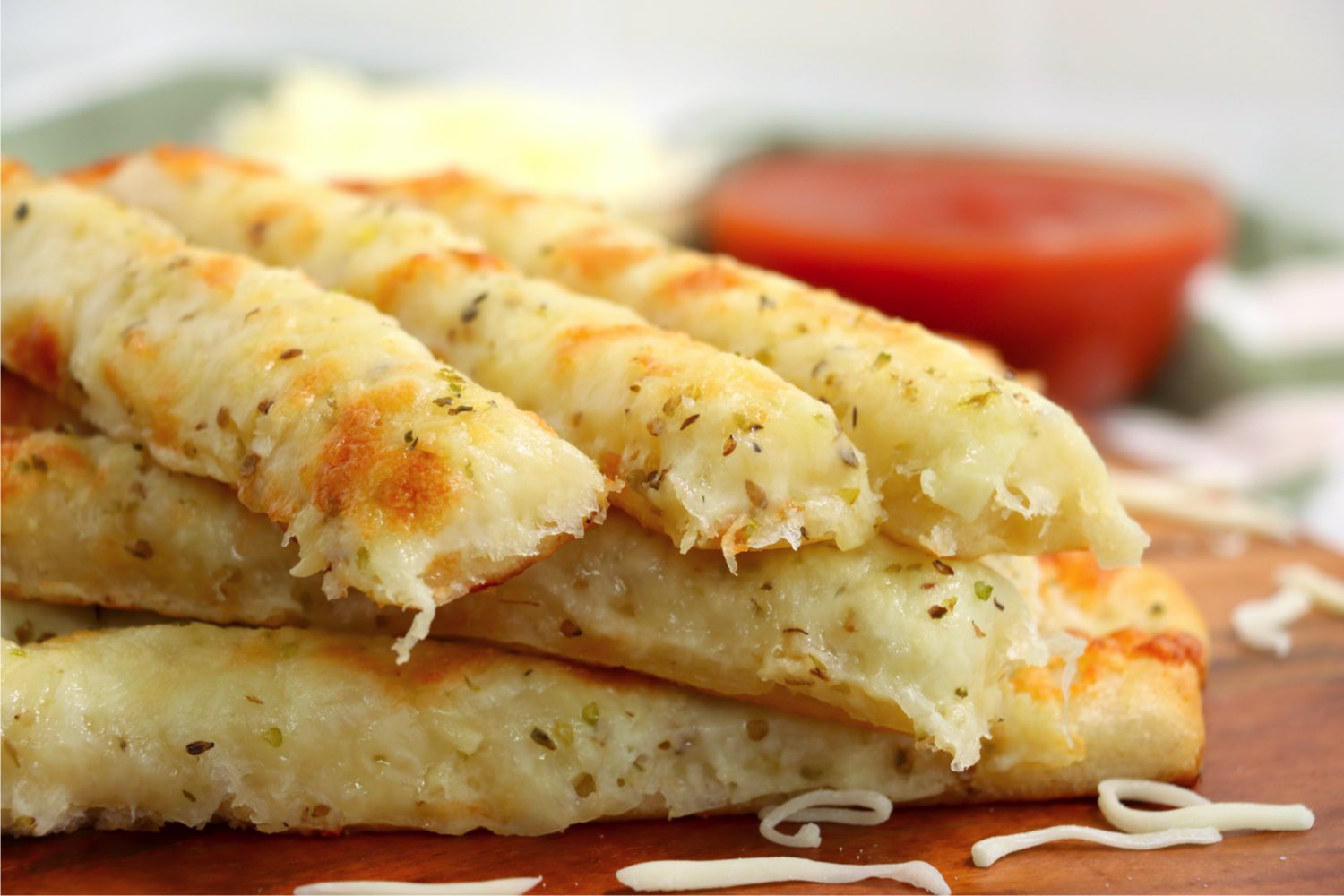 cheesy breadsticks in front of bowls of dipping sauce