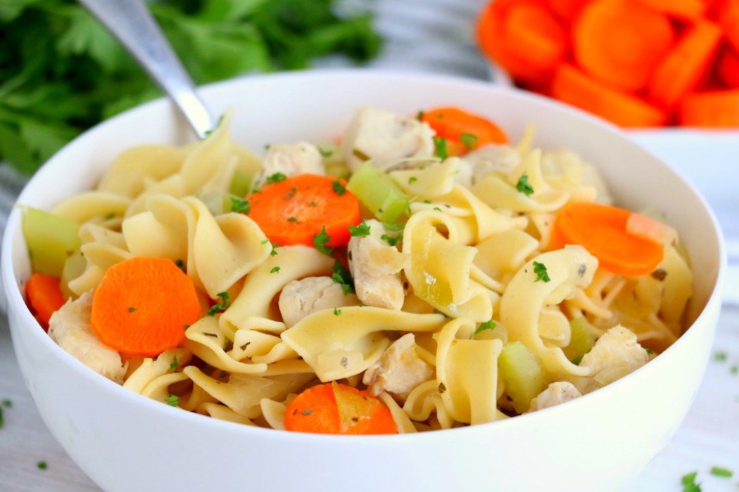 chicken noodle soup in white bowl with spoon