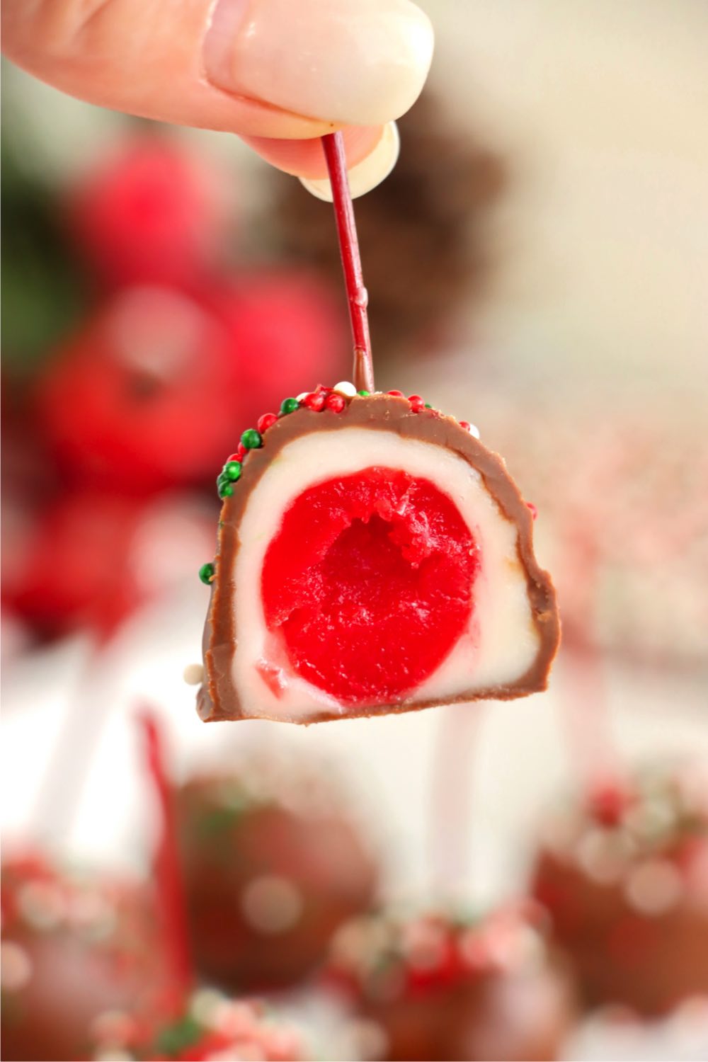 holding the stem of a chocolate covered cherry