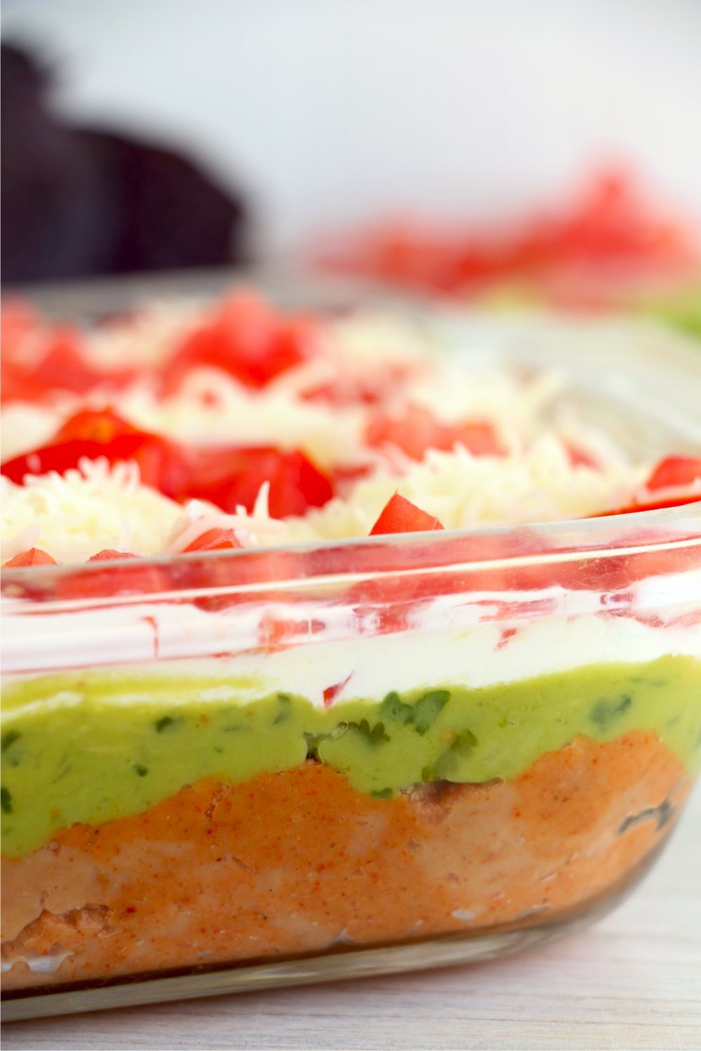 layers of taco dip seen through the side of a glass baking dish