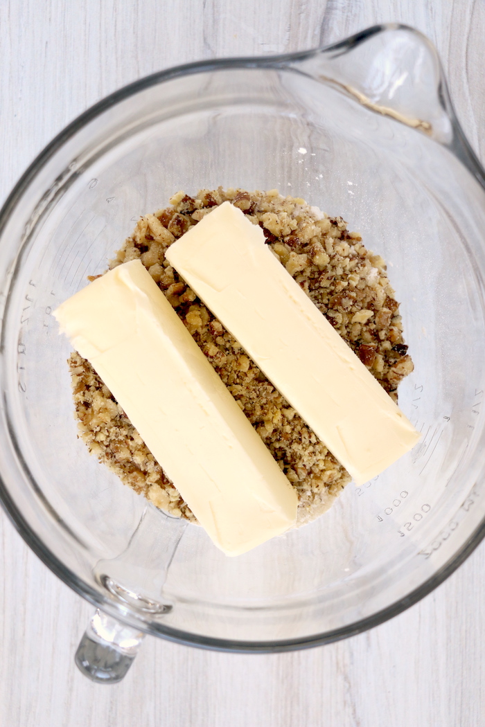 two sticks of butter on top of crushed walnuts