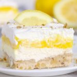 Lemon lush dessert on a plate with lemons in the background