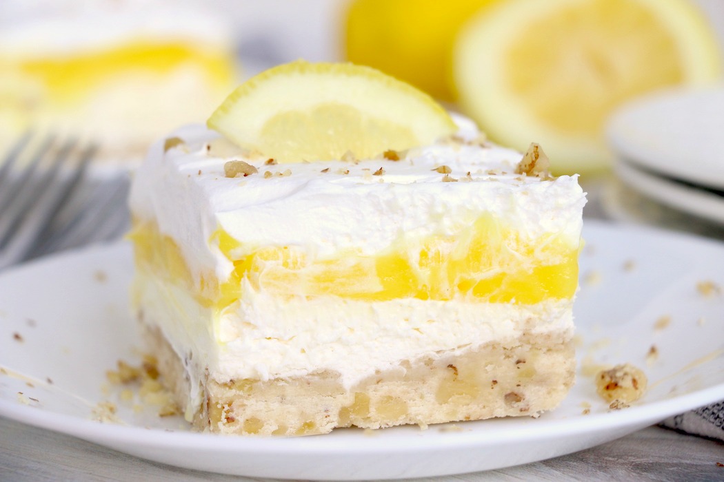Lemon lush dessert on a plate with lemons in the background
