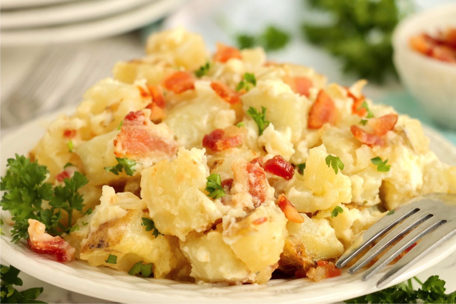 A close up of cooked potatoes and bacon on a plate