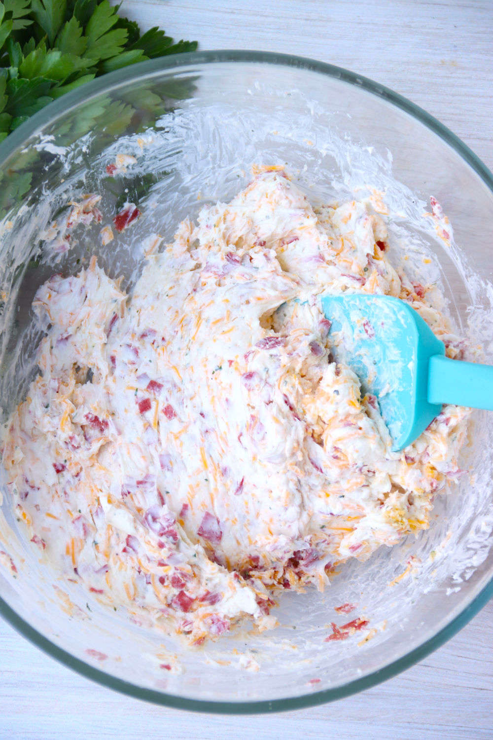 Mixing ingredients for cheese ball in glass bowl