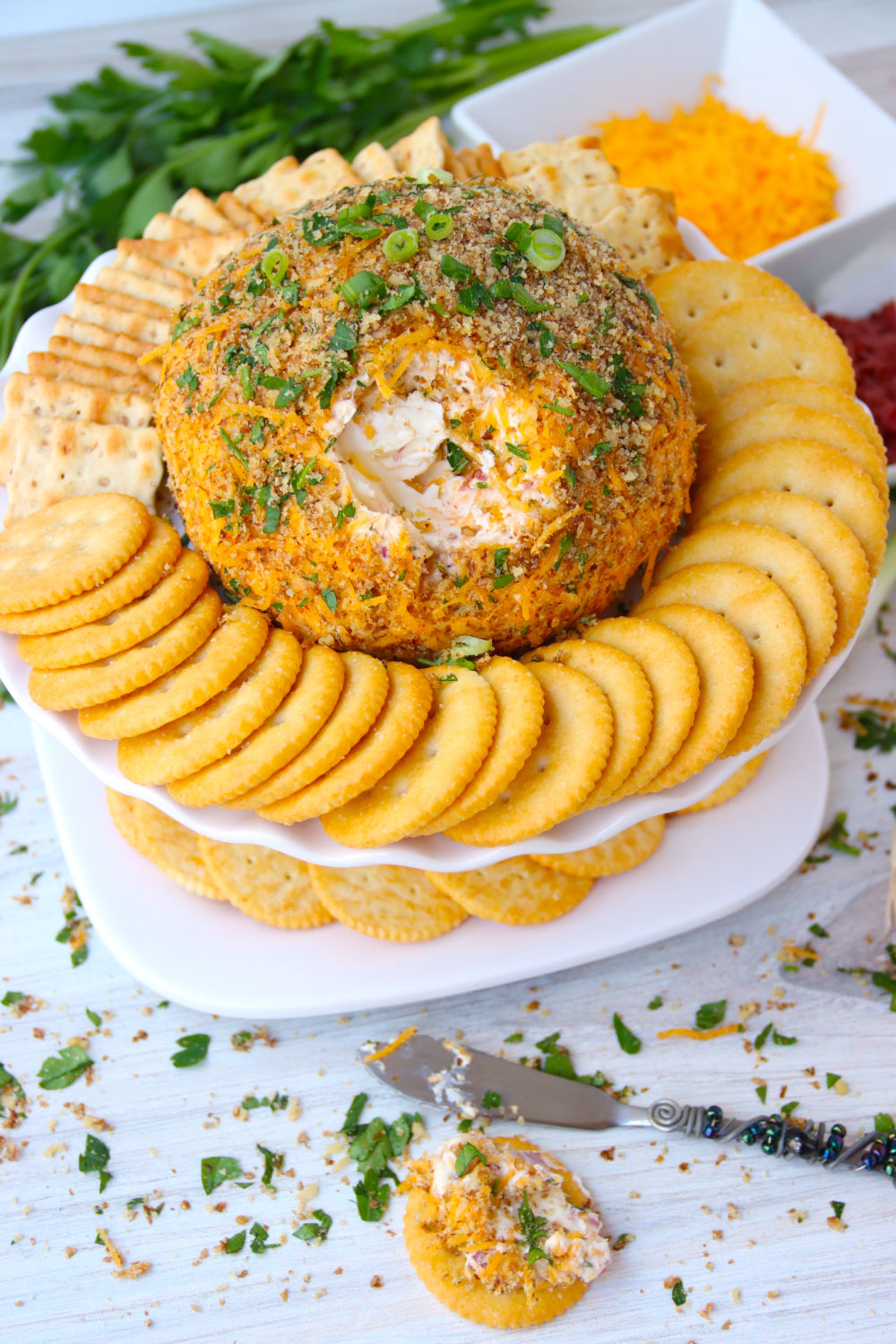 Cheese ball on a cake stand surrounded by crackers
