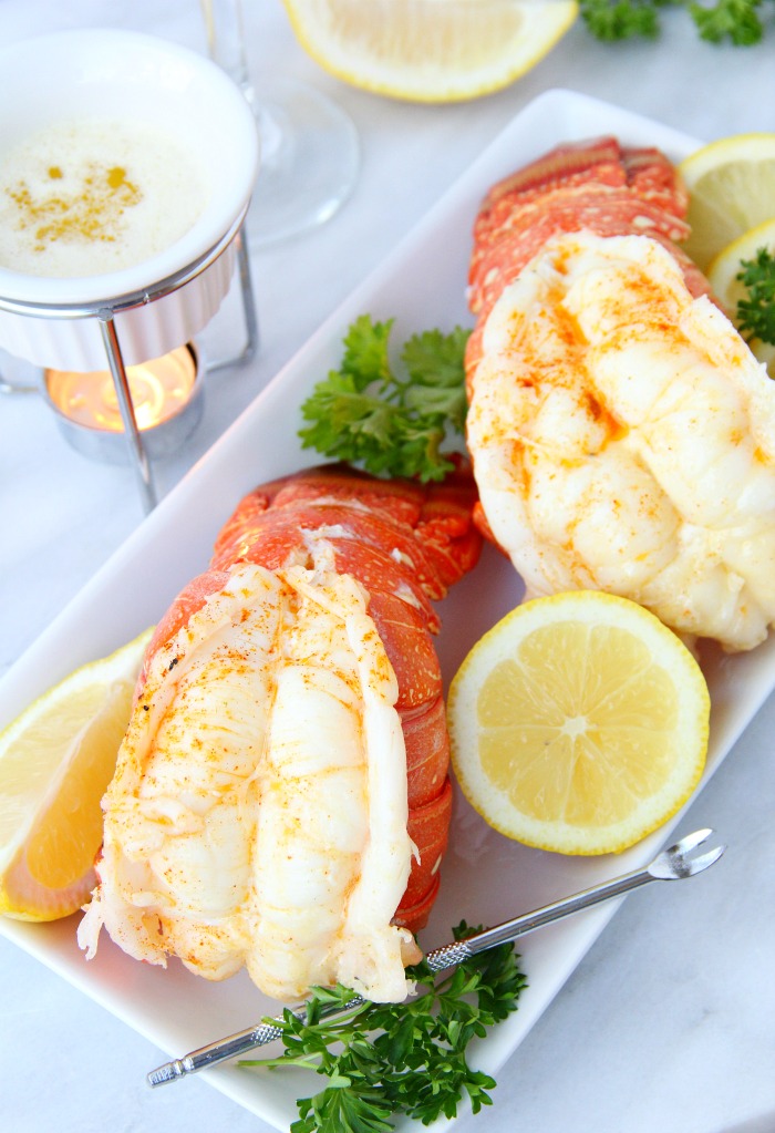 lobster tails on plate with lemon and melted butter on the side