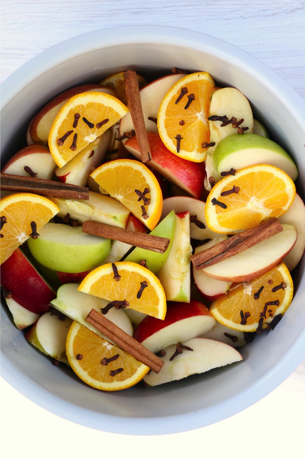 Ninja Foodi cooking pot filled with fresh fruit slices, cloves and cinnamon sticks