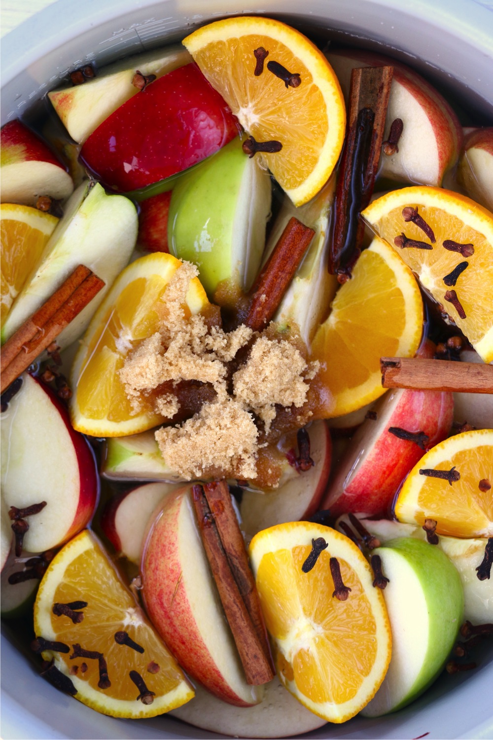 Adding brown sugar to Ninja Foodi cooking pot with fresh fruit and spices