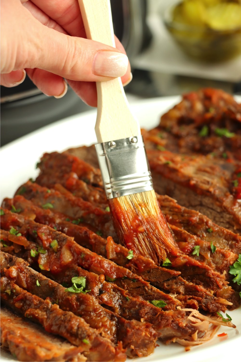 brushing sauce on a sliced beef brisket