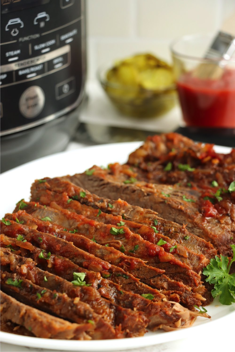 Sliced beef brisket in front of Ninja Foodi pressure cooker