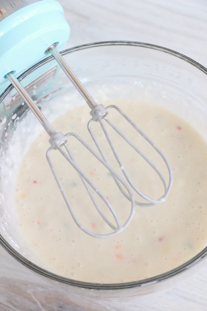 using a hand mixer to blend cake batter
