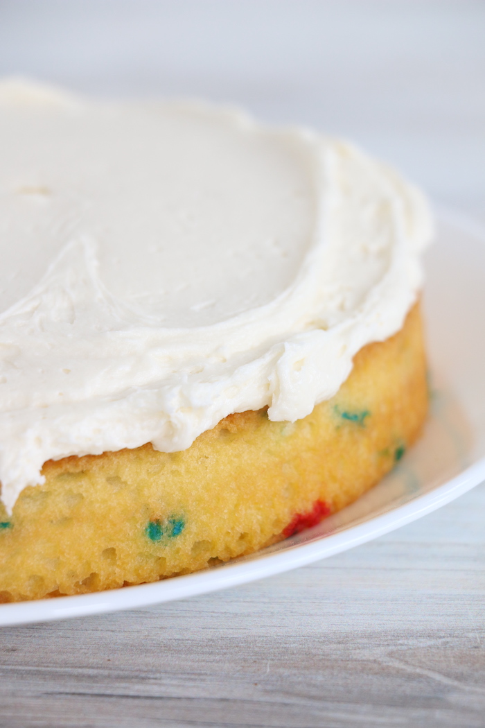 frosting spread on first layer of confetti cake