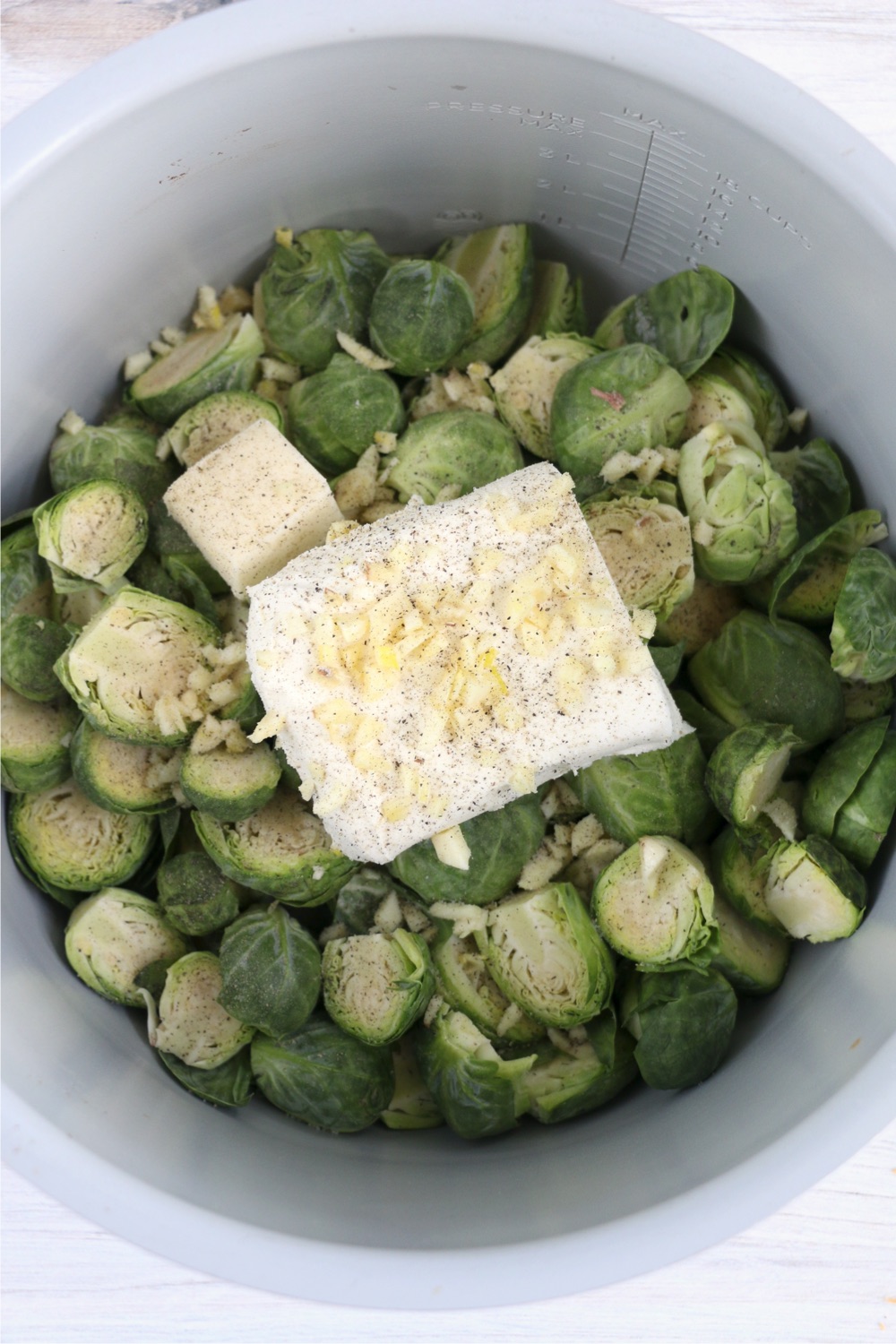 cream cheese, butter, garlic and seasonings on top of brussels sprouts in Instant Pot