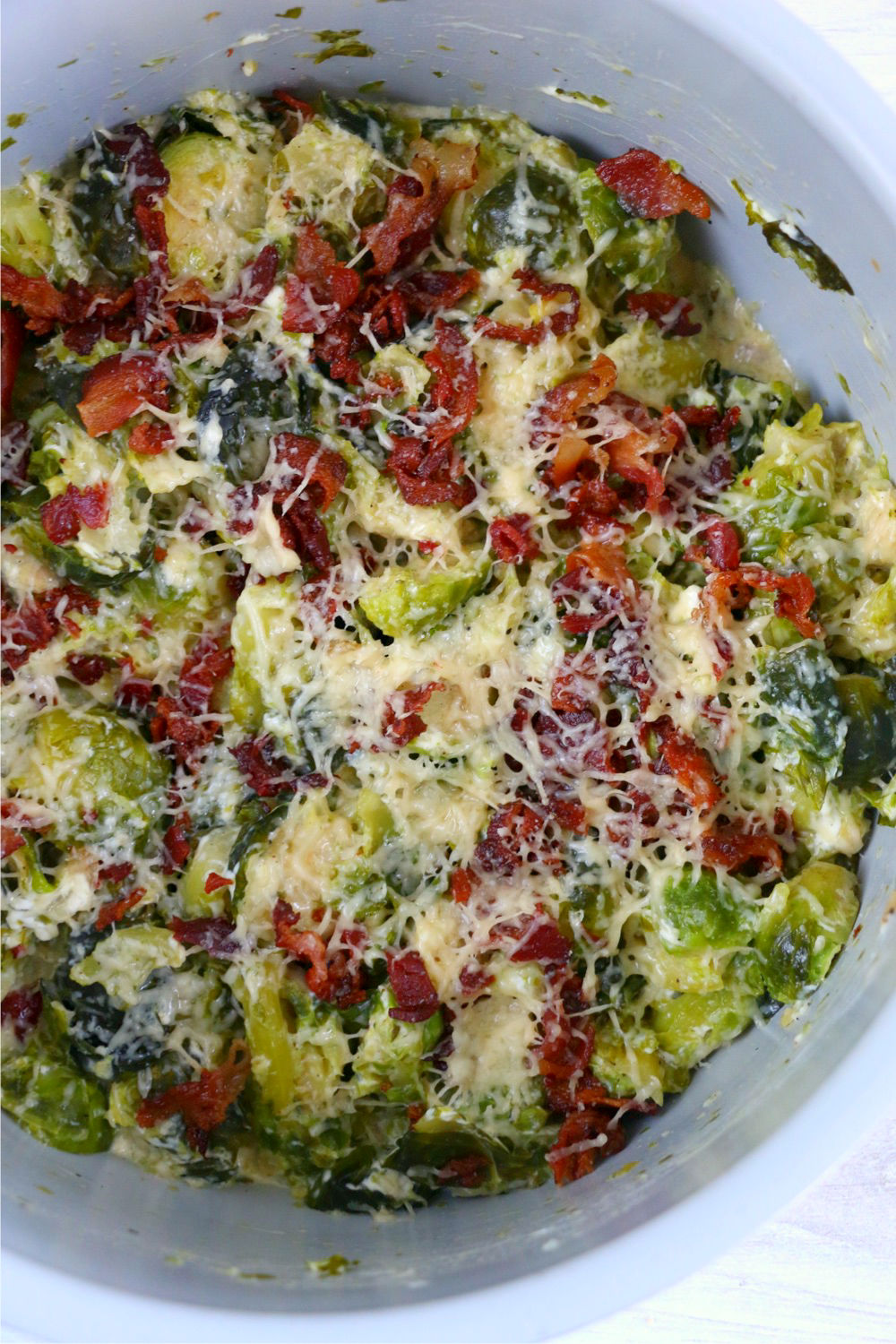 Melted parmesan cheese and bacon on top of Brussels Sprouts in Foodi cooking pot