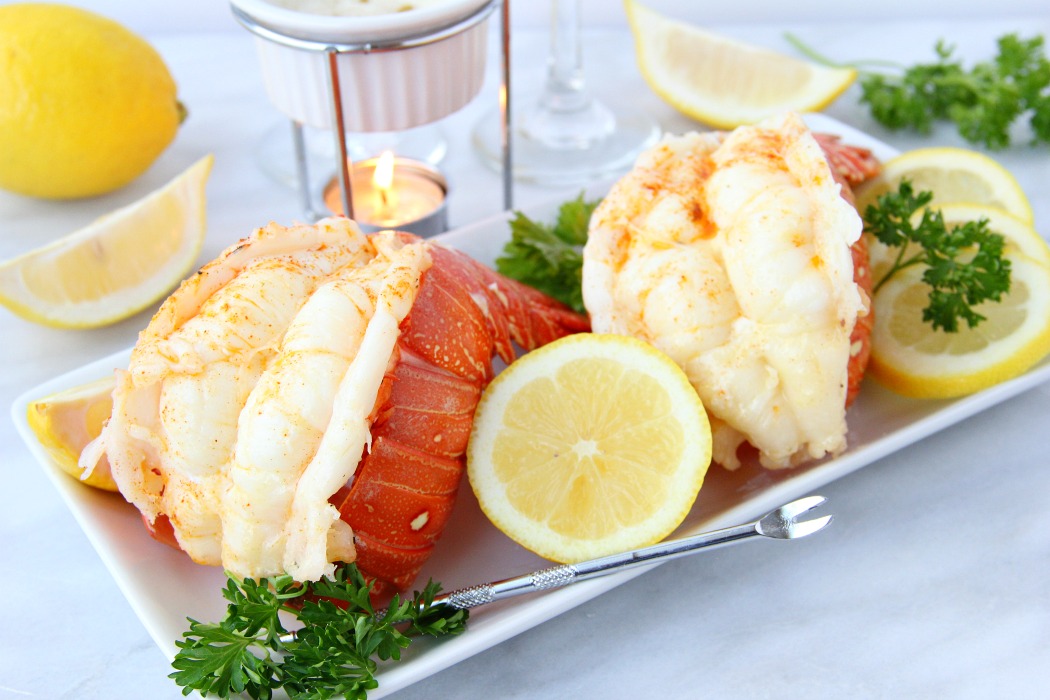 Lobster tails with lemon and melted butter in background