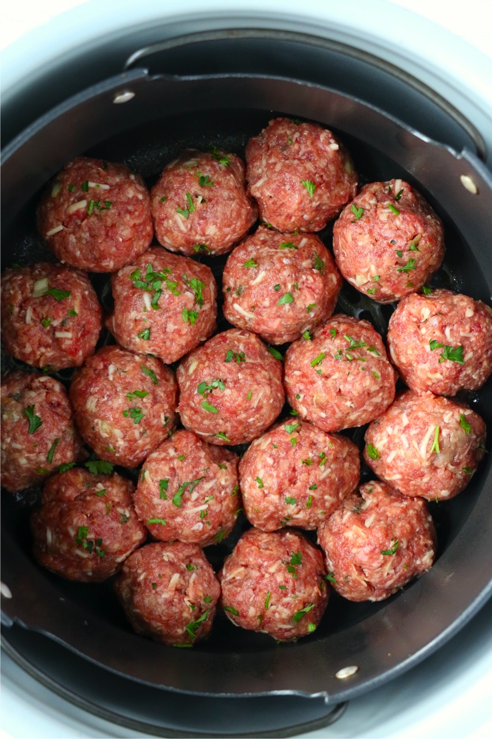 air fryer basket filled with uncooked meatballs