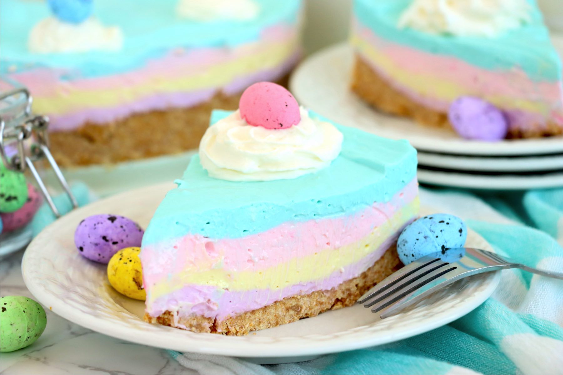 small white plate with a piece of layered Easter cheesecake
