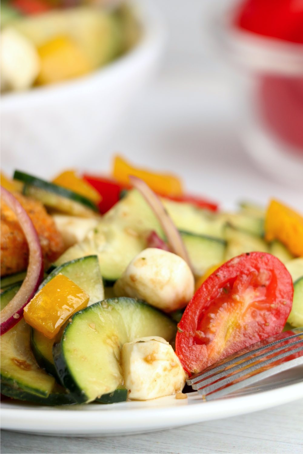 tomatoes, cucumbers and mozzarella in salad on white plate