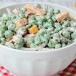 Easy Pea Salad - A summer salad perfect for potlucks and gatherings. Crisp green peas float alongside bacon, cheddar cheese and thinly sliced red onion in a sweet and creamy dressing.