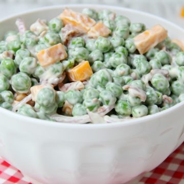 Easy Pea Salad - A summer salad perfect for potlucks and gatherings. Crisp green peas float alongside bacon, cheddar cheese and thinly sliced red onion in a sweet and creamy dressing.