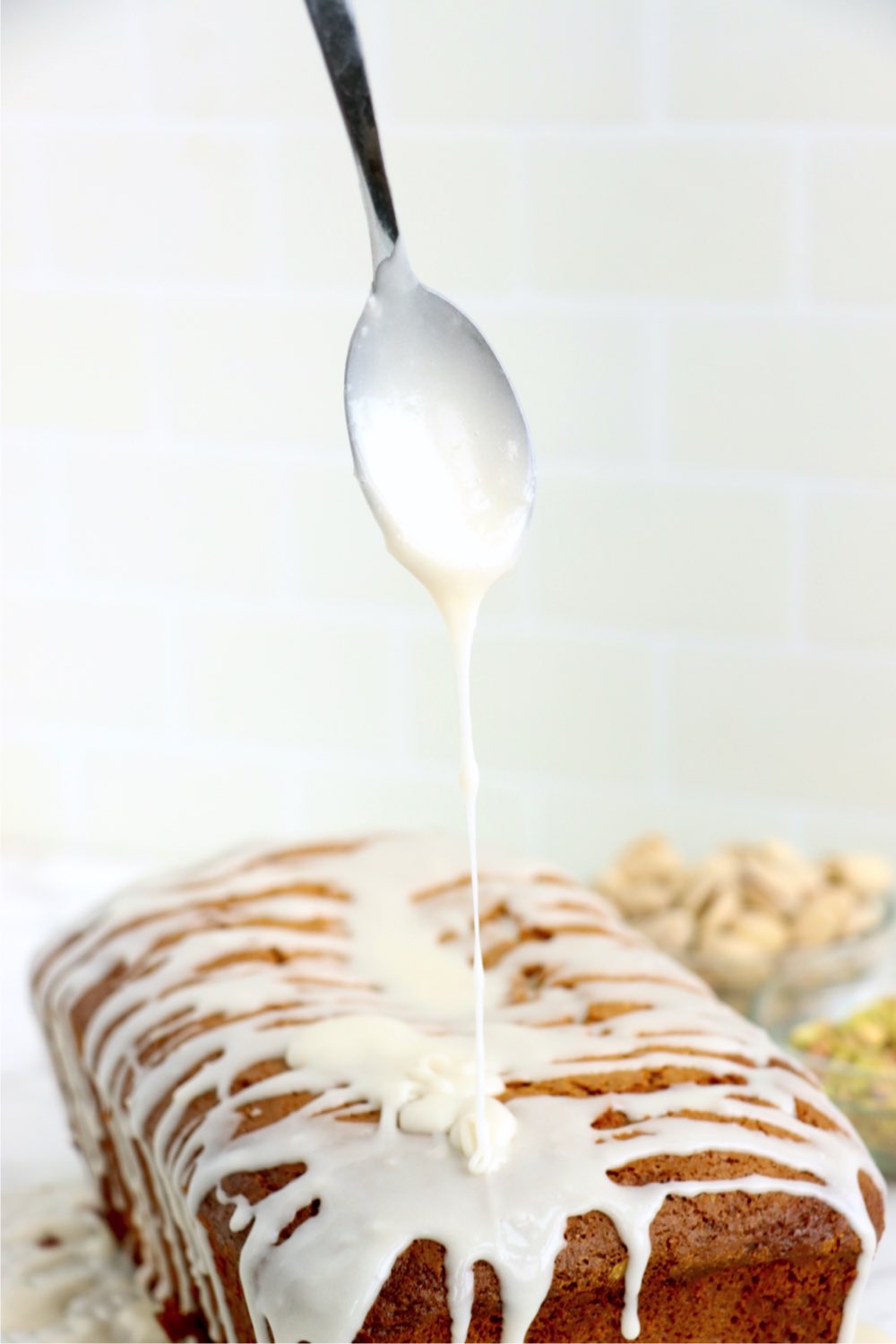 drizzling icing on a pistachio loaf