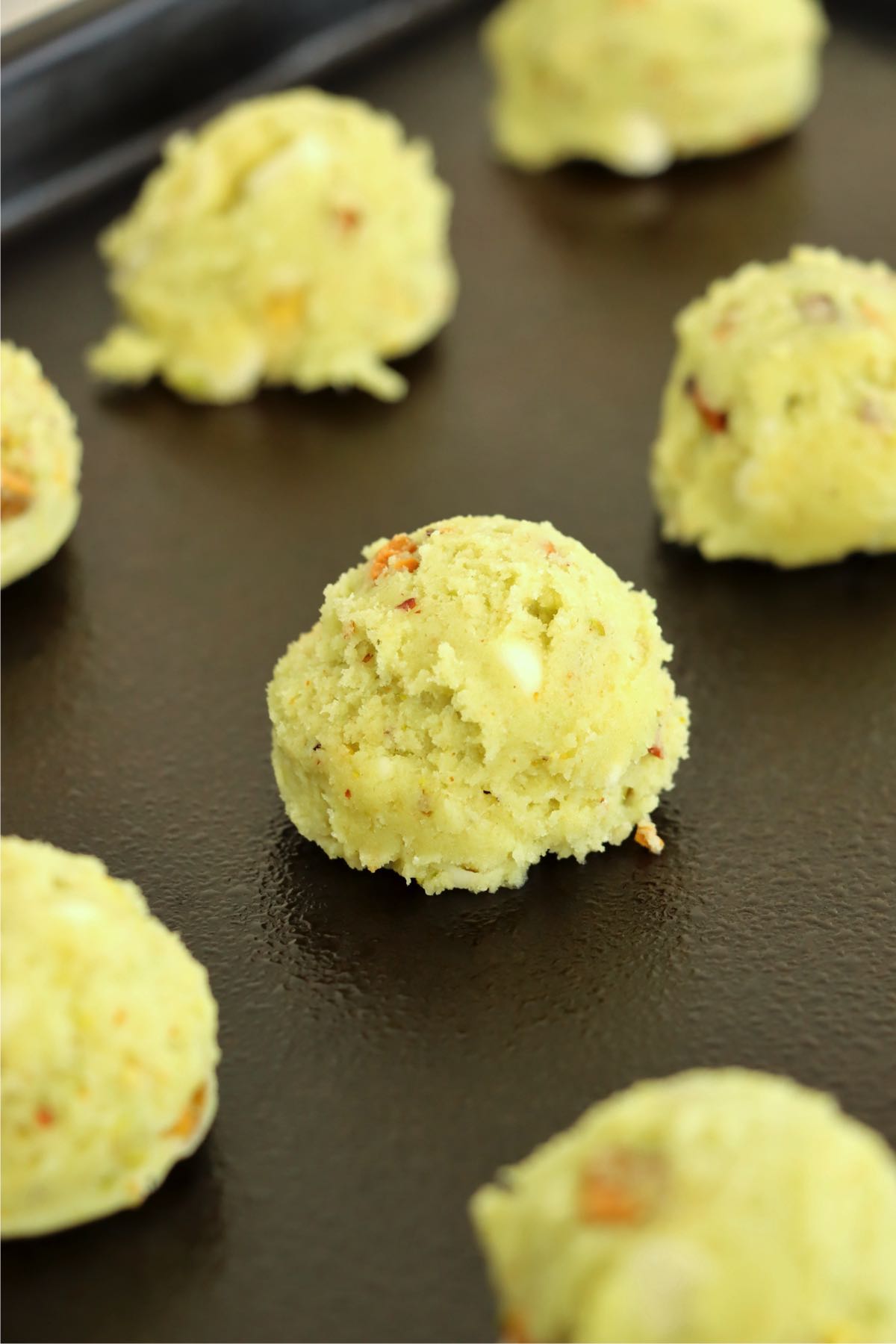 scoops of pistachio cookie dough on a baking pan