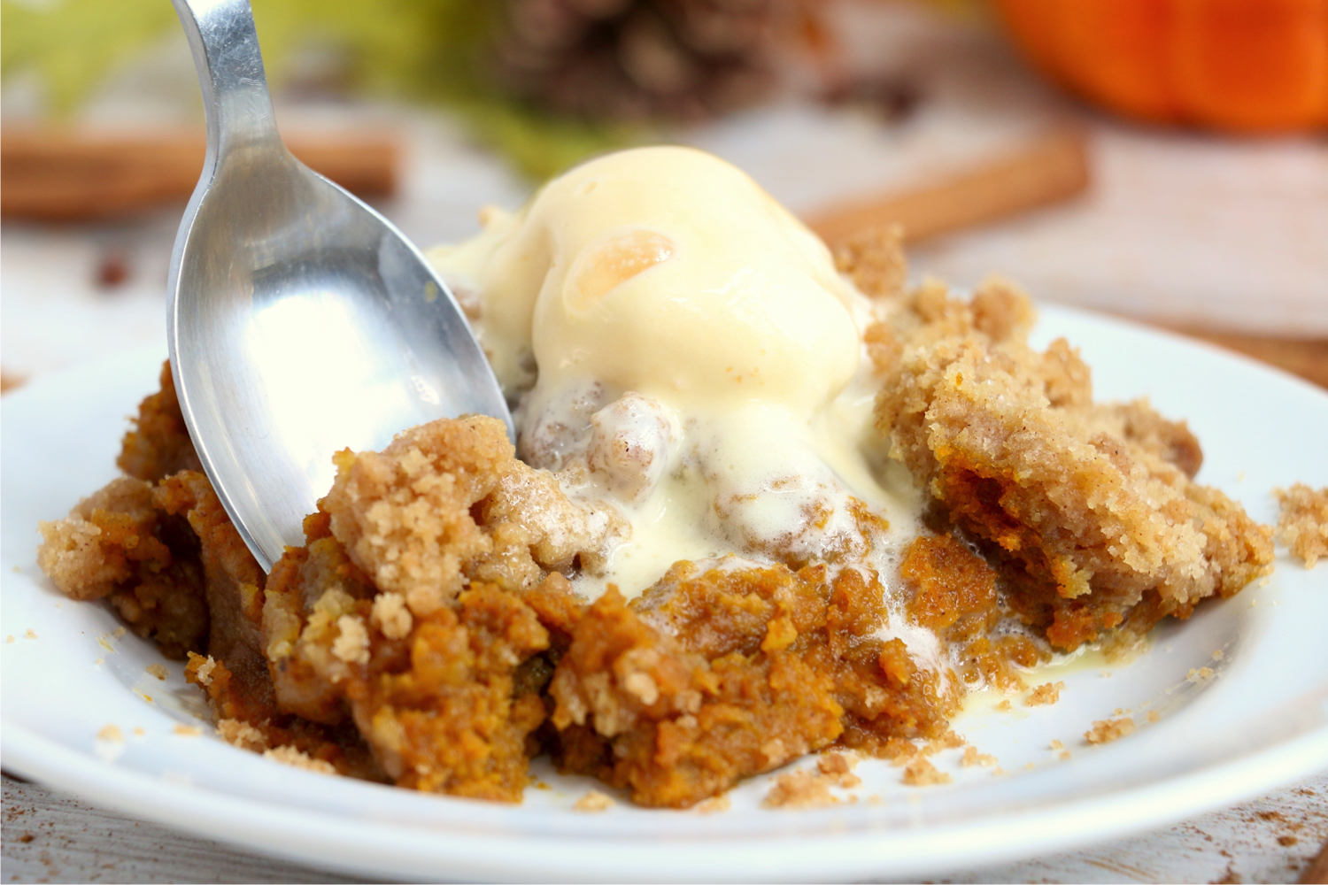 spoon digging into pumpkin dessert with ice cream