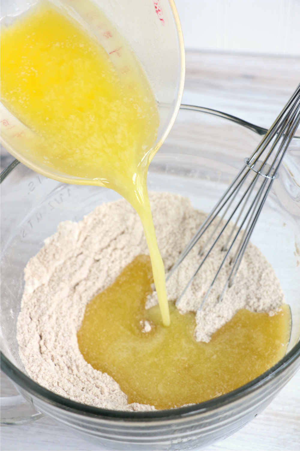 pouring melted butter into a flour mixture