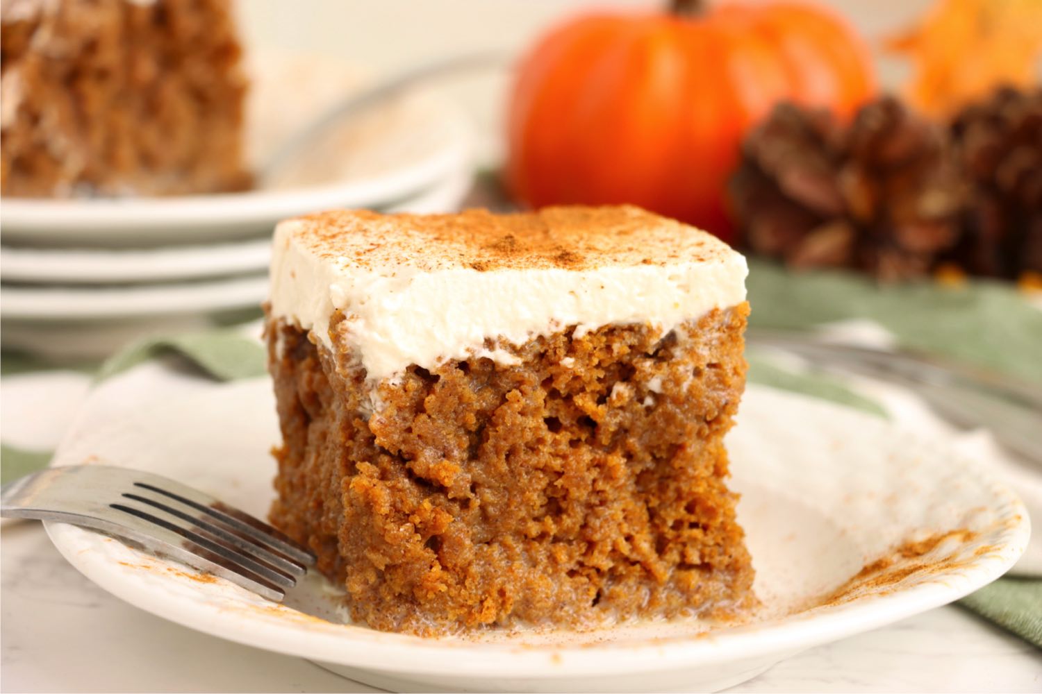 piece of pumpkin poke cake garnished with cinnamon