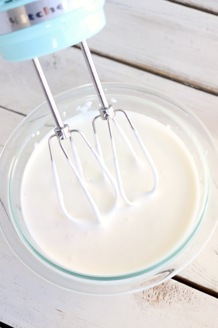 Beating heavy whipping cream and sugar in a glass bowl