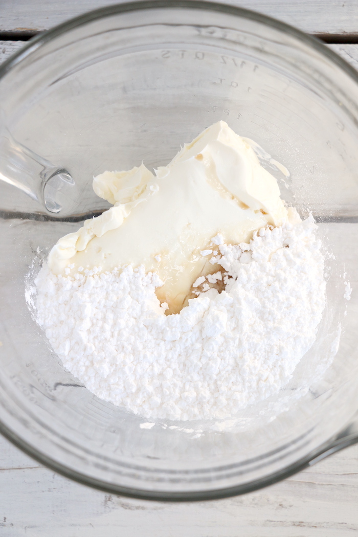 Glass bowl filled with cream cheese, powdered sugar and vanilla