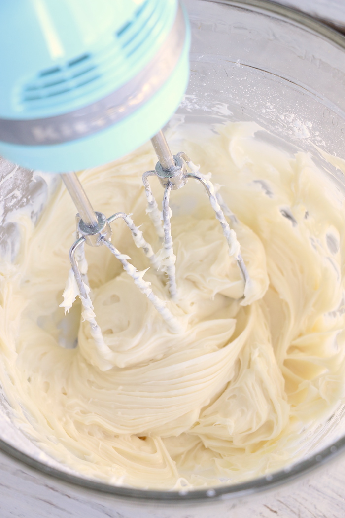 Whipping cream cheese, powdered sugar and vanilla in a glass bowl