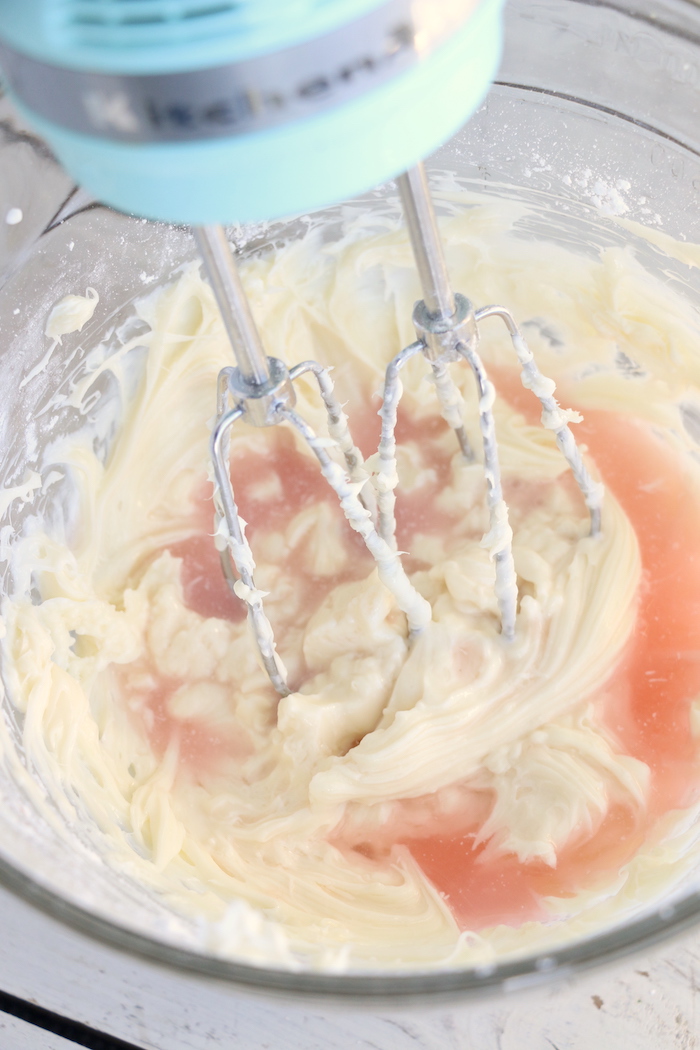 Adding pink lemonade to fruit dip mixture in glass bowl