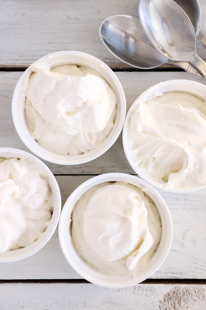 Four white containers of fruit dip