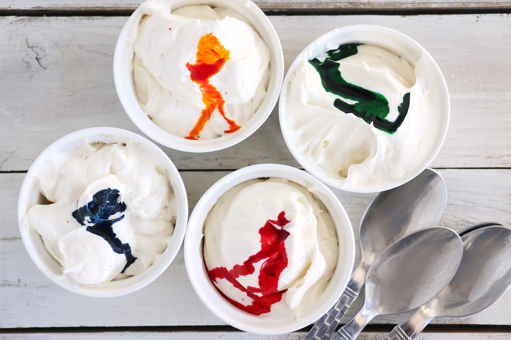 Adding food coloring to containers of rainbow fruit dip