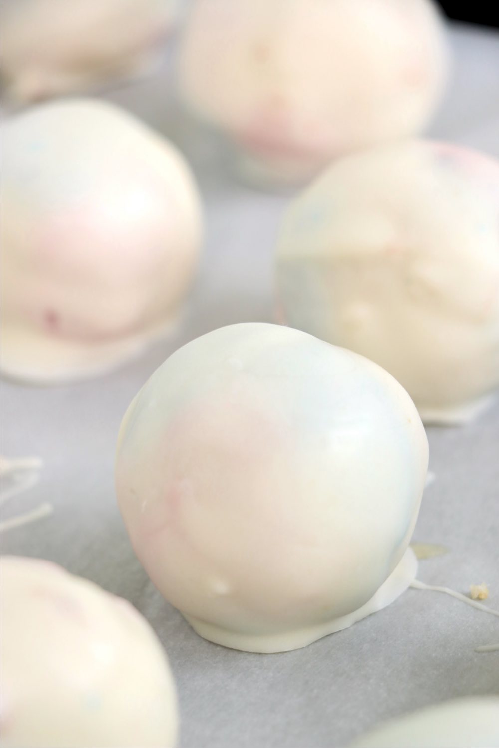 Truffles on a baking sheet covered with white almond bark.
