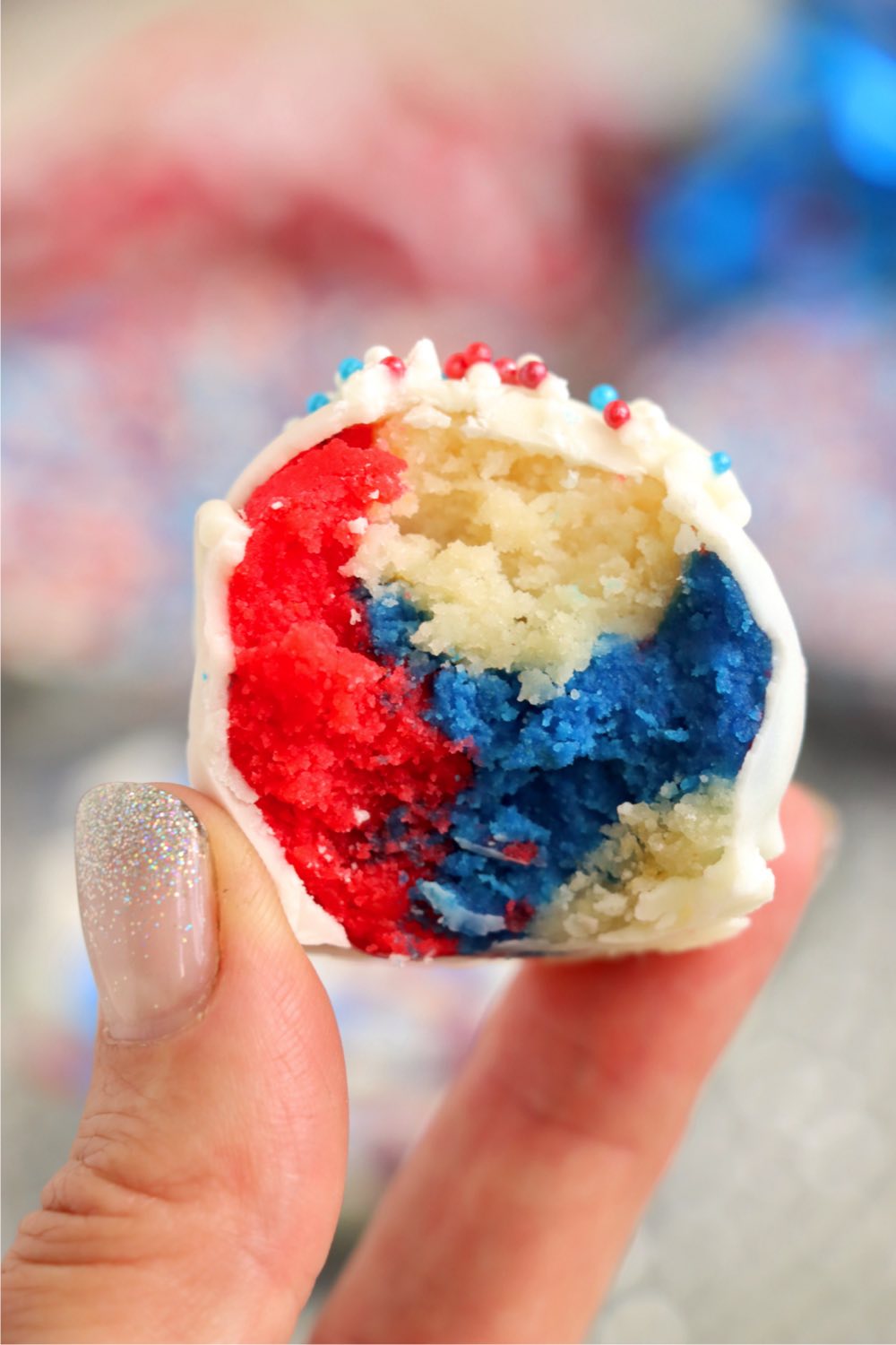 fingers holding a half eaten red, white and blue truffle.