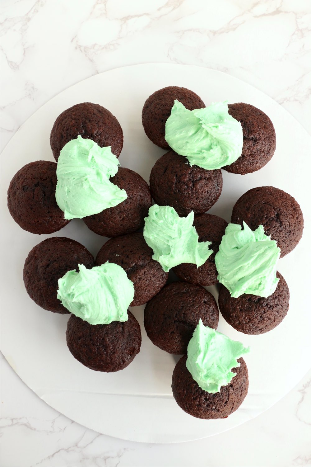 Spreading green frosting onto chocolate cupcakes