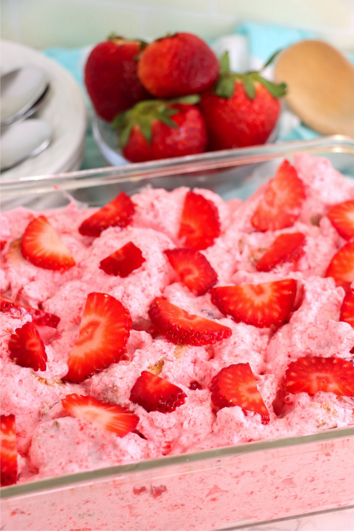 Glass cake pan filled with strawberry gelatin dessert and topped with fresh strawberries