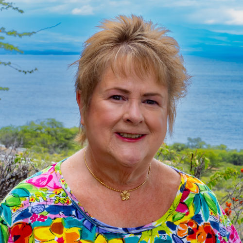 Lady standing in front of the ocean with a Hawaiian shirt