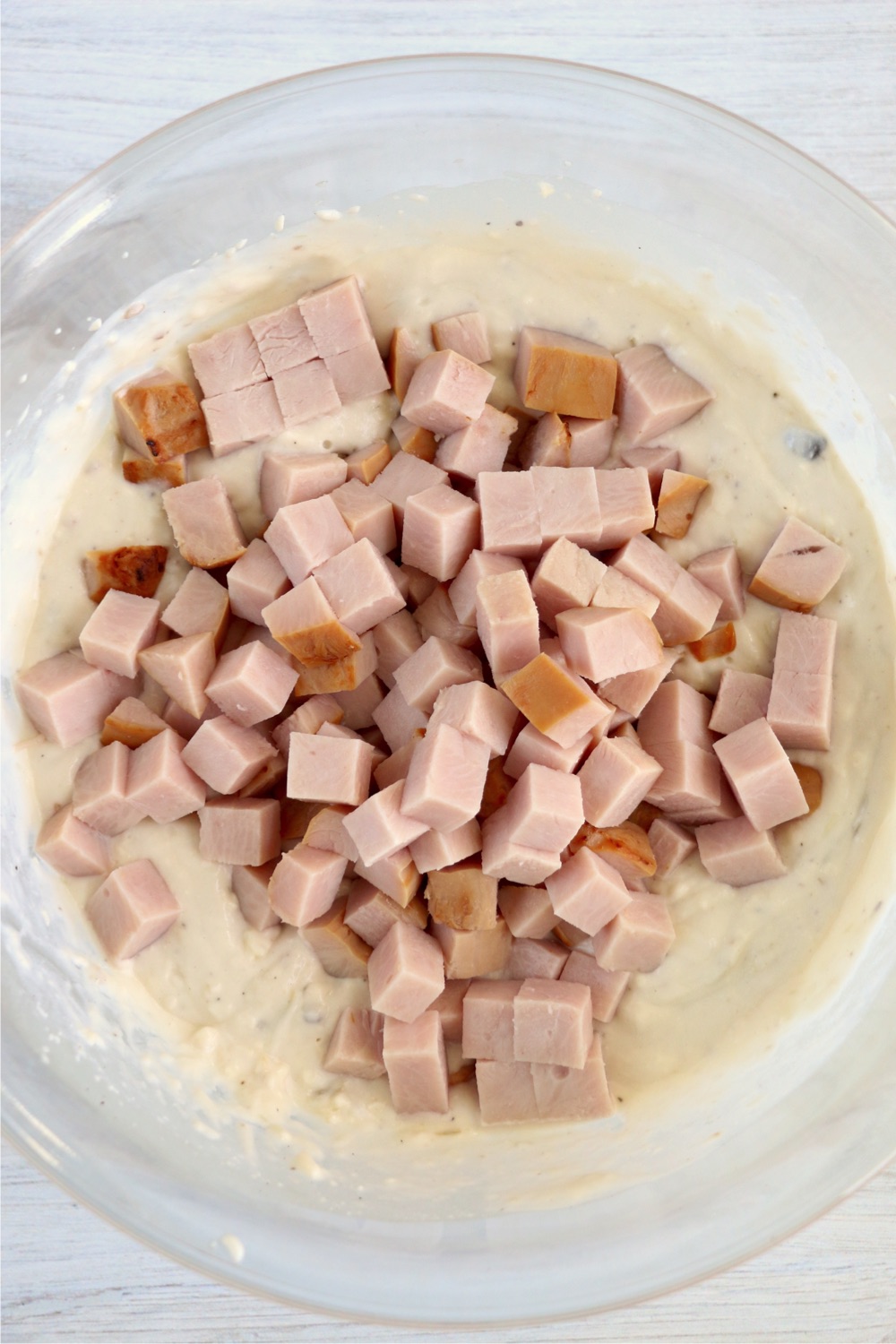 Cubed turkey added to sauce mixture in glass bowl