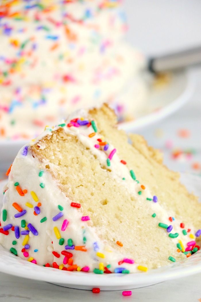 Piece of vanilla wacky cake with frosting and sprinkles