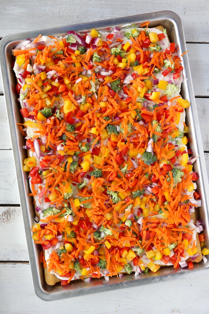 Halloween Veggie Pizza - A spooky themed graveyard pizza featuring a flavorful ranch cream cheese covered crust, topped with colorful veggies and "tombstone" crackers.