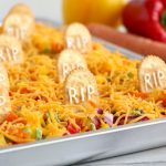 Halloween Veggie Pizza - A spooky themed graveyard pizza featuring a flavorful ranch cream cheese covered crust, topped with colorful veggies and "tombstone" crackers. 