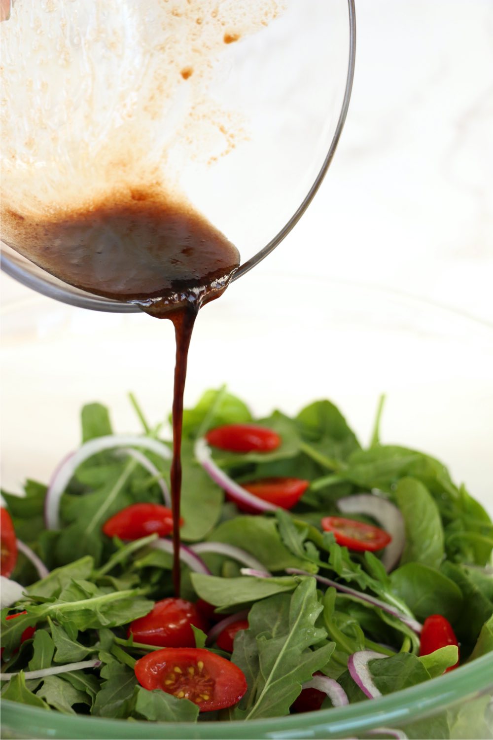 drizzling balsamic dressing on salad