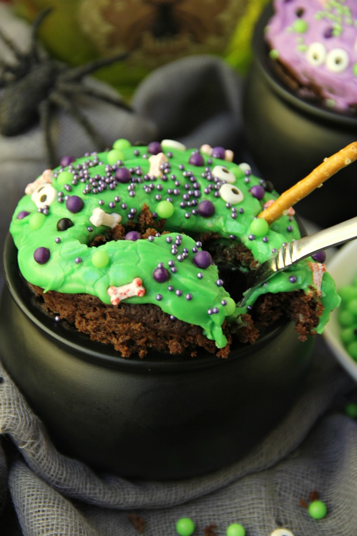 Witch Cauldron Mug Cake - A chocolate mug cake made in a ceramic witch cauldron with halloween-themed frosting and sprinkles!