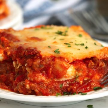 close up shot of a large piece of lasagna on a plate
